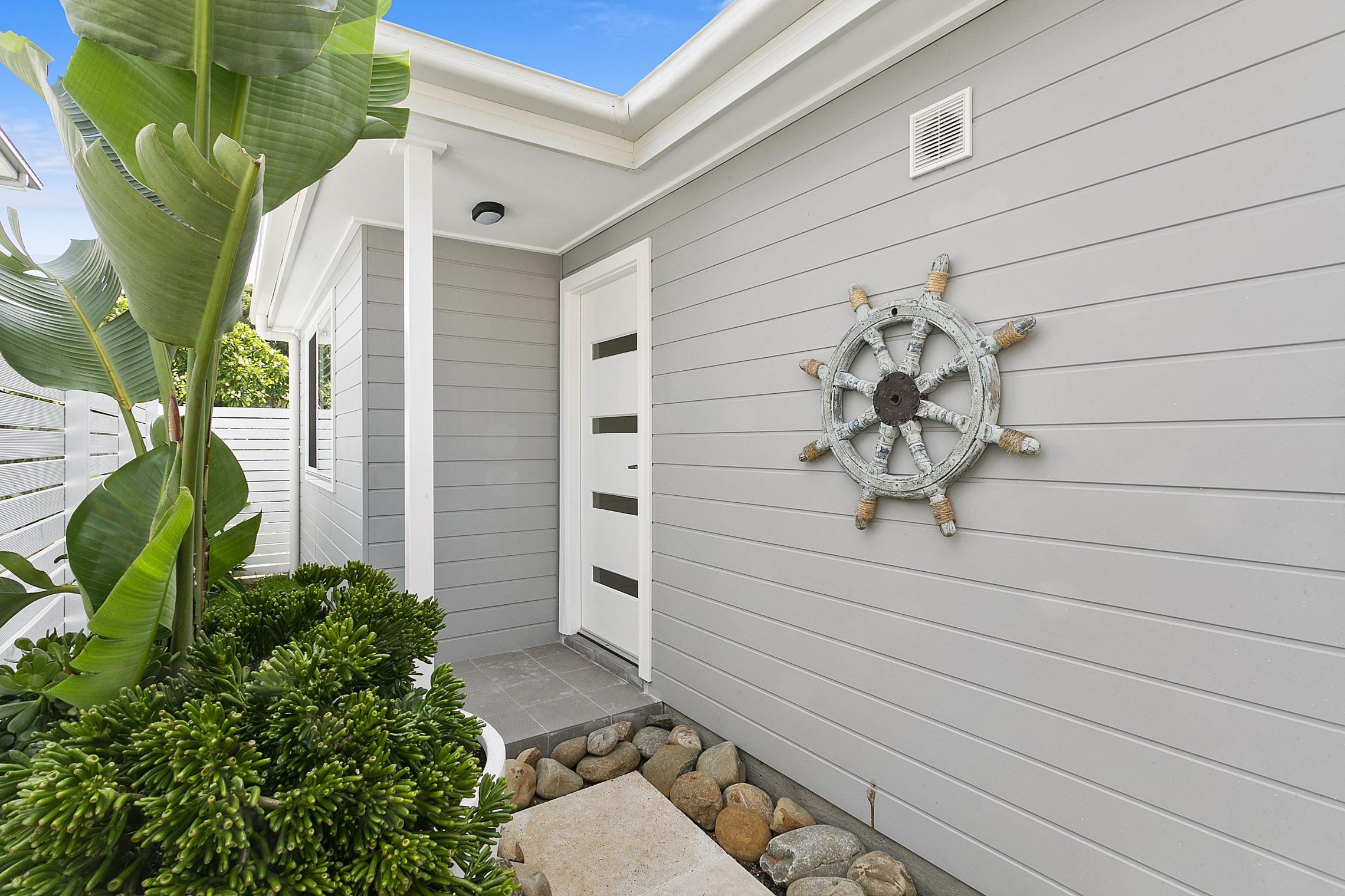 Modern entry way to granny flat with decorative sailor's wheel on the exterior wall